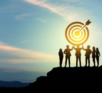 Goal setting towards planning for the future. Silhouettes of group businessmen holding target boards with flags planted on a mountain. Concept of a clear planning process and teamwork.